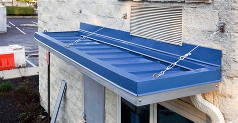 standing seam angled metal canopy detail with support bracket above|overhead supported canopy.